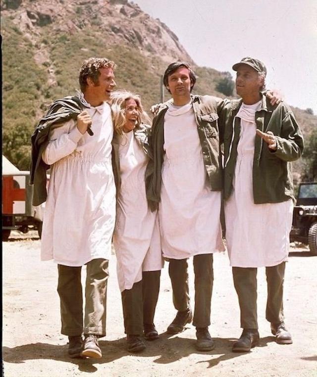 The cast of "M*A*S*H" shares a light-hearted moment, embodying the show's mix of humor and seriousness. Alan Alda (center) leads the way with his fellow castmates during a break from shooting