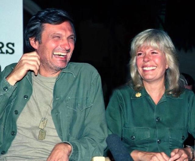 Alan Alda and Loretta Swit sharing a laugh behind the scenes - A candid moment between M*A*S*H stars Alan Alda (Hawkeye) and Loretta Swit (Margaret "Hot Lips" Houlihan) during a break from filming 